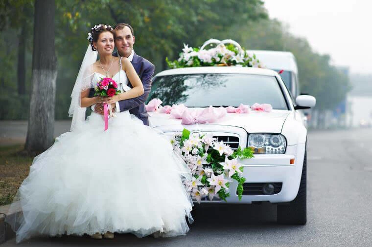 NEWLY WED COUPLE IN FRONT OF A WEDDING LIMOUSINE